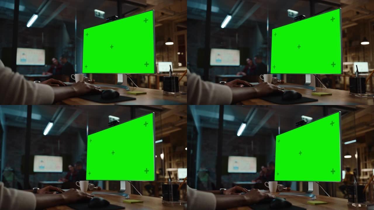 在繁忙的创意办公室中，一位黑人非裔美国人项目经理在台式计算机上进行视频通话，并带有绿屏模拟显示。男性