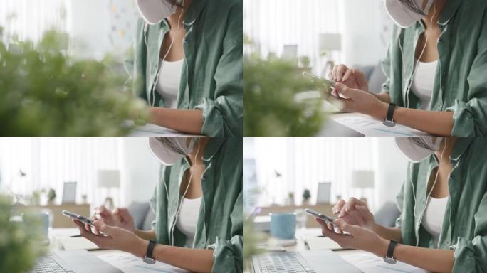 年轻的亚洲女性戴着医用口罩在电话里聊天忙碌的企业家在客厅里工作。