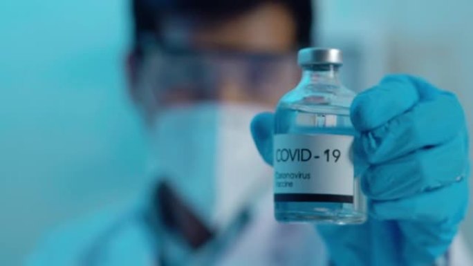 在实验室里，32岁的年轻男性亚洲科学家手拿疫苗展示。科学实验室的概念。