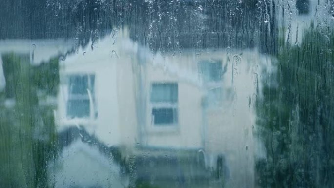 雨水从窗户向下流下，背景是房屋