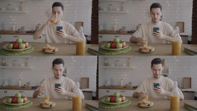 年轻人在家里的厨房里喝果汁和使用智能手机的肖像