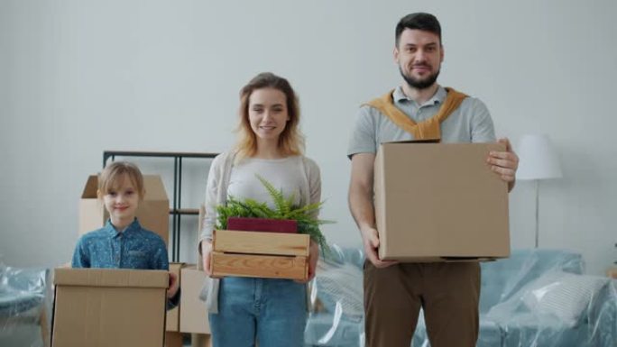 男人和小女孩幸福的家庭在搬迁到新公寓时拿着箱子