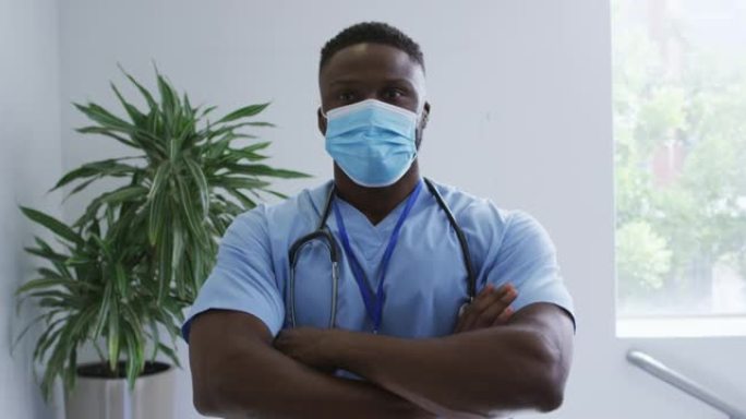 非裔美国男医生戴着磨砂膏和口罩，在医院交叉双臂的肖像