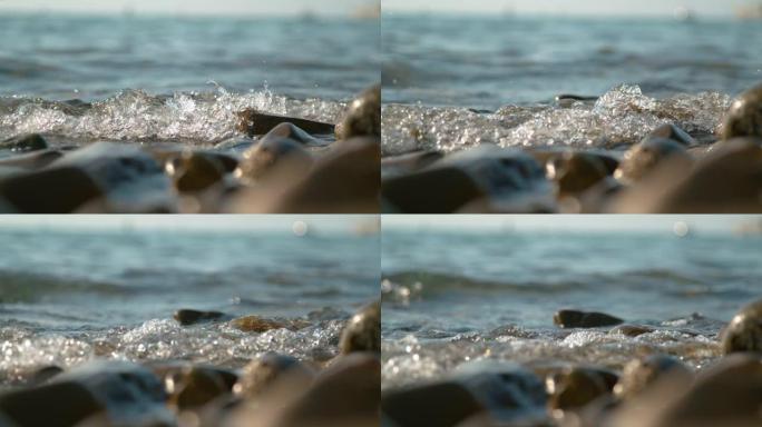 特写: 玻璃状的海水溅到空旷的海岸的棕色鹅卵石上。