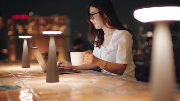 女人在夜间在笔记本电脑上工作，在屏幕上看