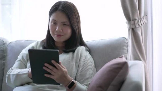女人使用数字平板电脑，呆在客厅沙发上