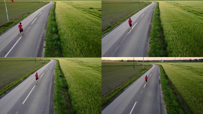 男运动员在被草地包围的高速公路上慢跑的鸟瞰图，跟踪户外追逐的镜头