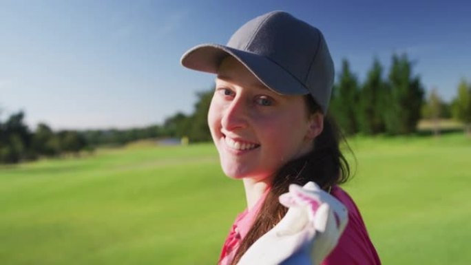 女高尔夫球手的肖像在高尔夫球场上背对着金球杆微笑