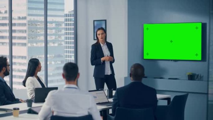 办公室会议室会议演示: 年轻积极进取的高加索女商人演讲，使用绿屏色度键墙电视。成功向多民族投资者群体