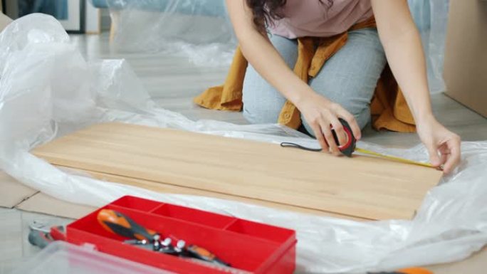 年轻女子在搬迁过程中使用工具制作架子做木制品