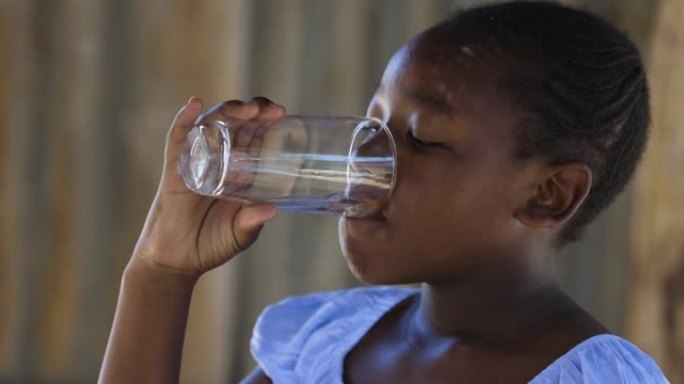 贫穷。不平等。可爱的年轻黑人非洲女孩在小镇上用玻璃杯喝水