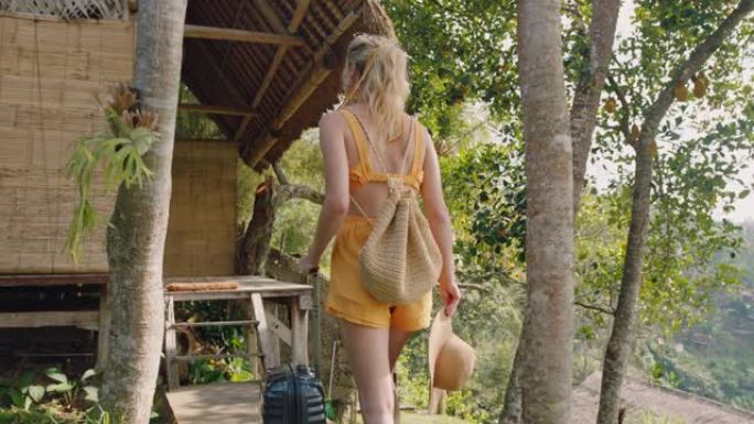 带着手推车包的旅行女人在异国情调的暑假到达热带酒店度假胜地，步行到小屋