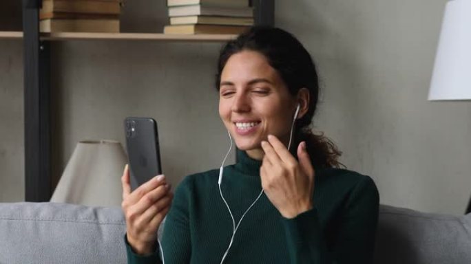微笑积极的年轻女子拿着手机视频通话。