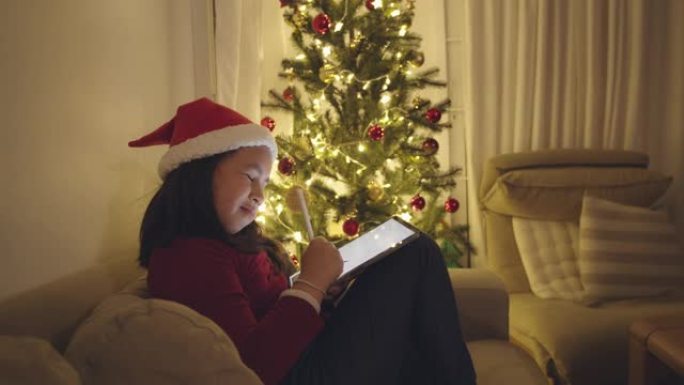 小女孩在圣诞节期间在家中的数字平板电脑上画画。