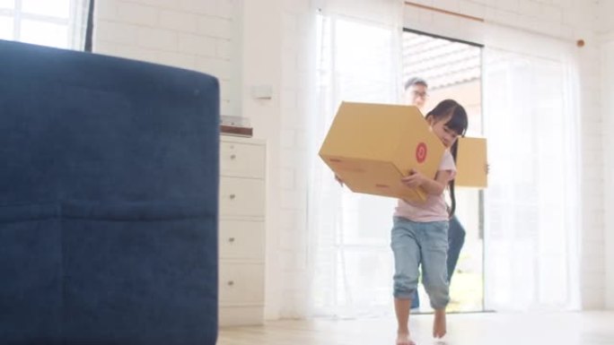 日本妈妈、爸爸和孩子微笑快乐地拿着纸板箱，移动物体走进家。