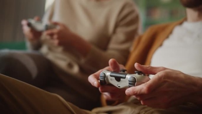 幸福的夫妇坐在沙发上玩电子游戏，使用控制器。恋爱中的竞争女友和男友在家里一起玩在线视频游戏。近距离聚