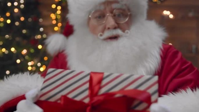 放大视频，圣诞老人看着相机，向我们展示了一个礼品盒