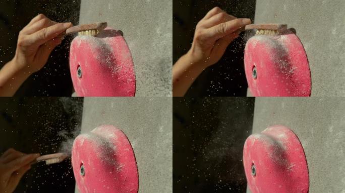 宏观: 女性登山者使用刷子摆脱粘在粉红色卷曲上的镁
