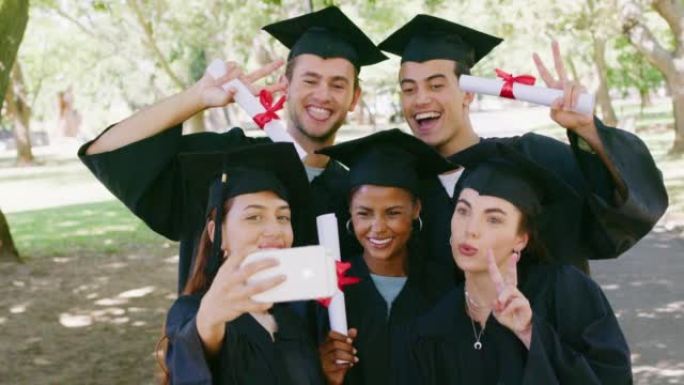 大学校园毕业典礼后，一群毕业生使用电话进行社交媒体自拍照。大学毕业后使用技术和持有学位的男性，女性或