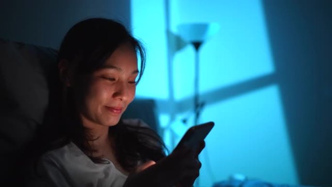 亚洲女性晚上使用智能手机床
