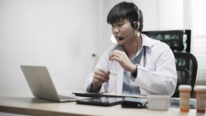 亚洲男子医疗在办公室的笔记本电脑上有视频呼叫远方病人