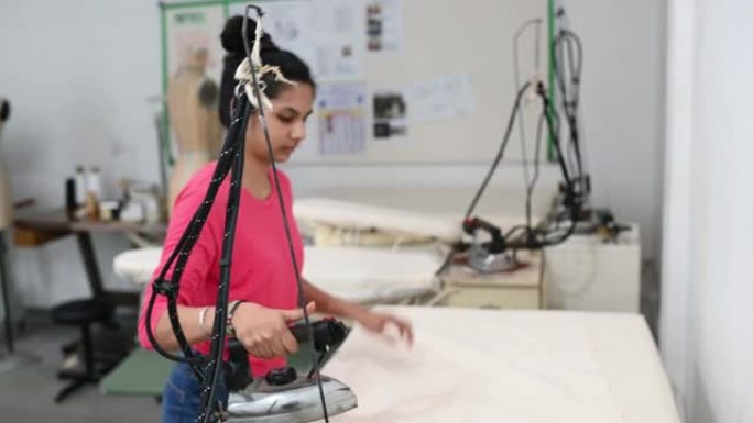 亚洲印度女性时尚大学生在大学车间做服装项目熨烫布料