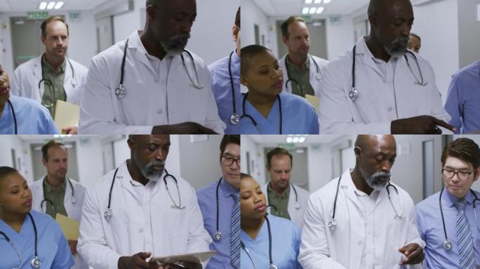 使用平板电脑和交谈在医院走廊上行走的男女医生的多元化群体