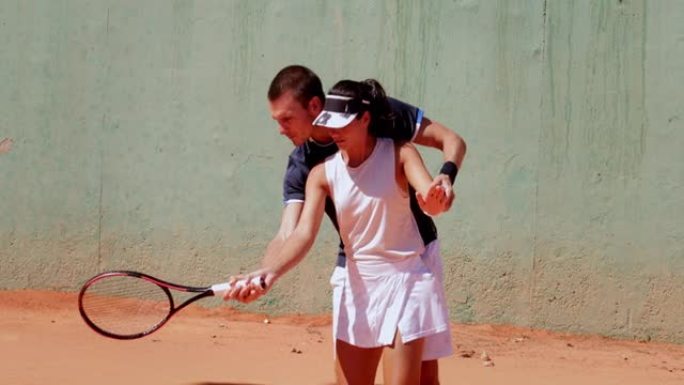 网球教练在红土场上教年轻女子网球