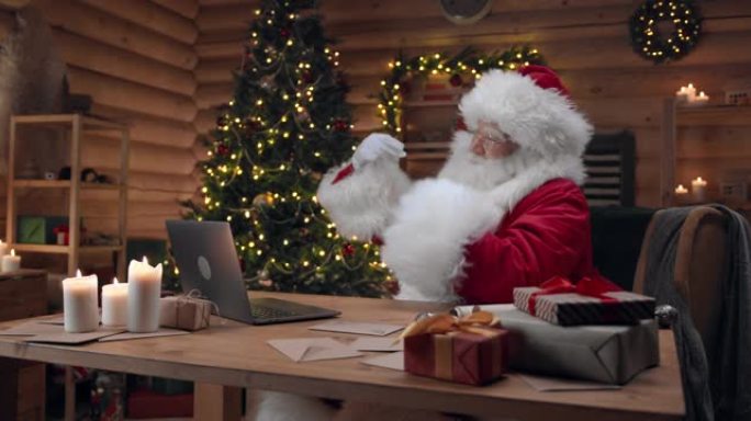 圣诞老人坐在他装饰的办公室里，讲述这个故事，双手指着他，坐在圣诞节的室内