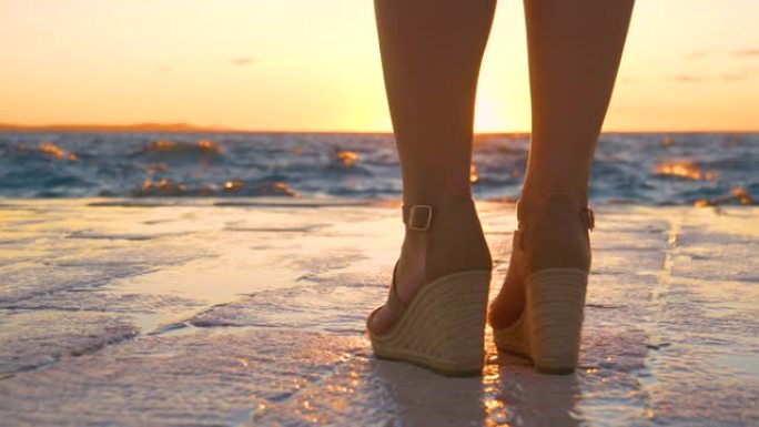 复制空间: 穿着高跟鞋的女性游客从石头走道观察日落。