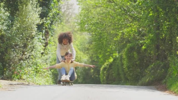 孩子们在户外玩得开心，男孩沿着乡间小路把女孩推滑板