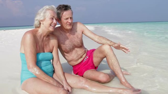 坐在美丽海滩上的高级夫妇