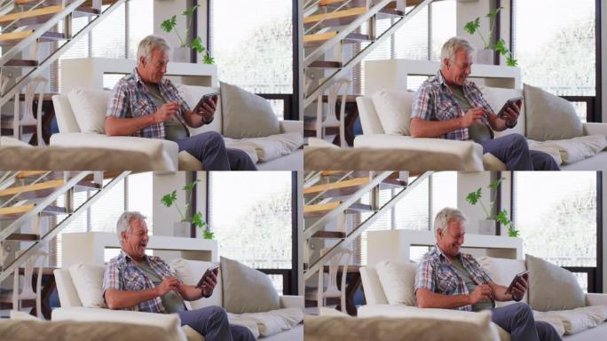 高个子白人坐在家里的沙发上在数字平板电脑上进行视频聊天