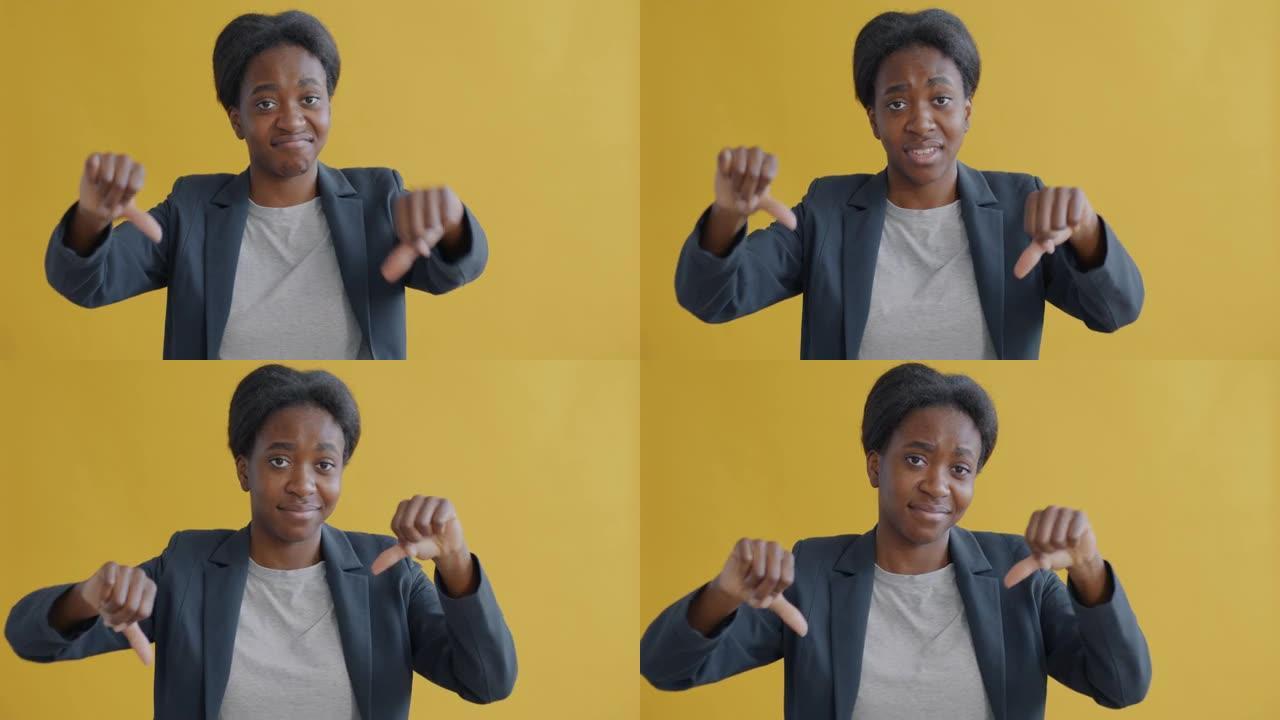 不高兴的非洲裔美国妇女表现出拇指朝下，看着相机表达负面情绪