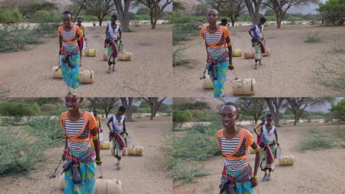 气候变化。干旱。水危机。特写正面视图。由于持续干旱，非洲妇女用塑料容器走路和滚动回家。肯尼亚