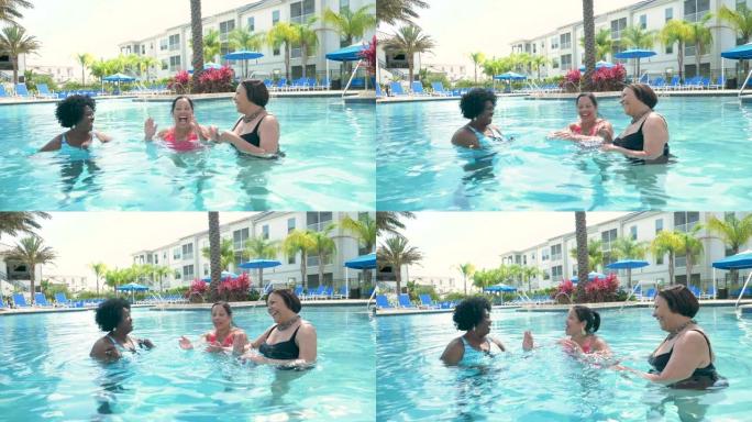 三名高级妇女在度假，在游泳池里聊天