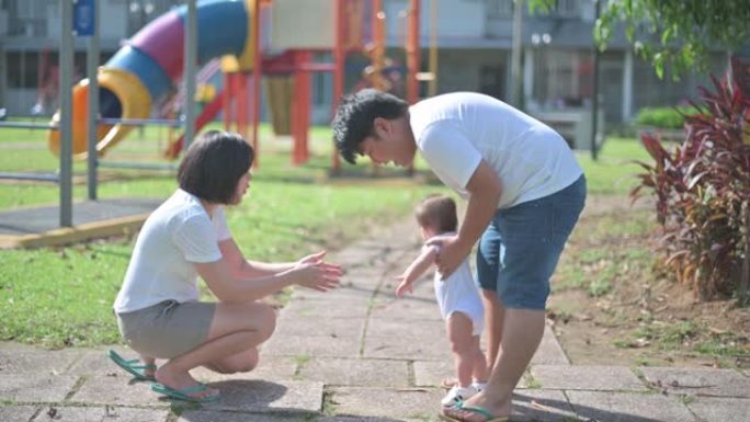 亚洲华裔家长教男婴学第一步清晨在公园散步