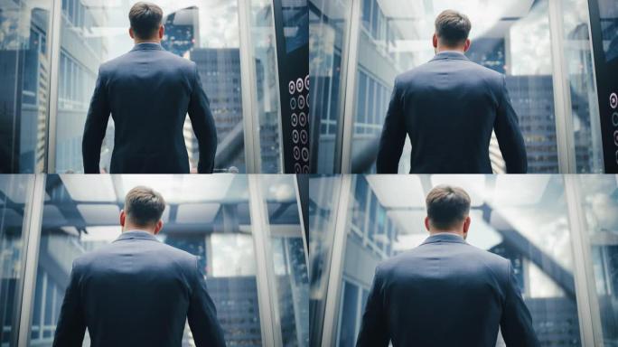 穿着西装的商人乘坐玻璃电梯到现代商务中心的办公室。男性在电梯的全景窗口外看着现代的市中心摩天大楼。回