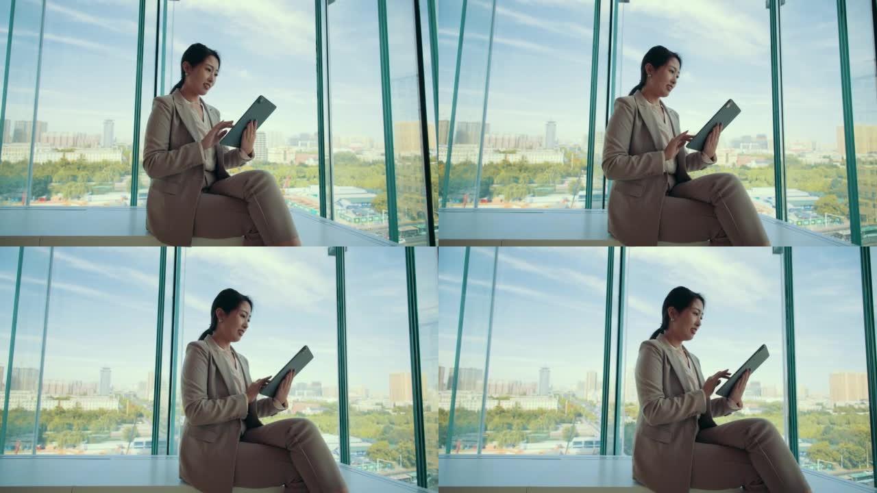 女商人坐在窗户前使用数字平板电脑