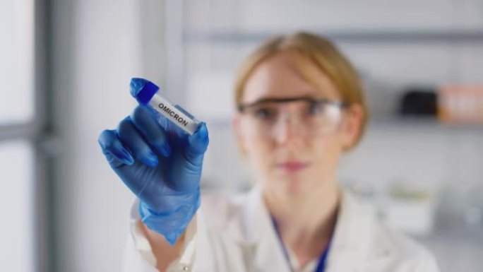 女实验室研究人员戴着安全眼镜，拿着标有欧米克隆的试管