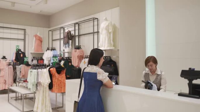 亚洲中国精品服装店女店主与顾客互动收银员用信用卡购物结账