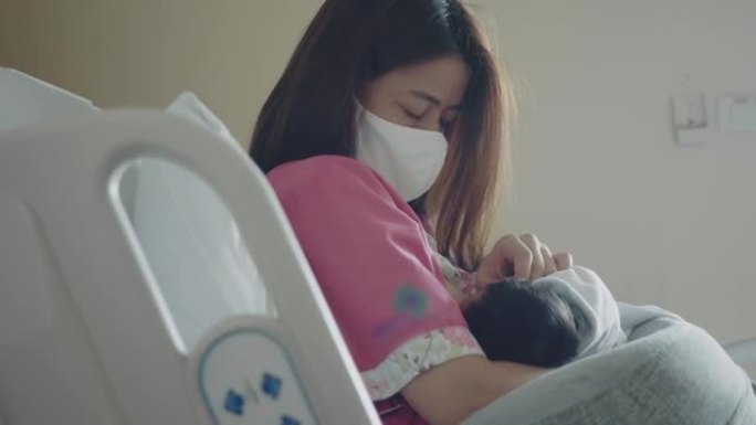母亲戴着口罩保护和新生儿住院。