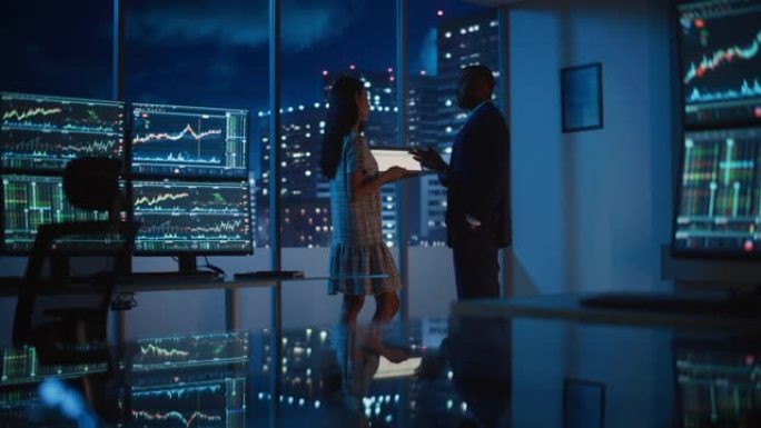 金融分析师在深夜工作时与投资银行家交谈。在平板电脑上聊天实时股票图表数据。商人在经纪机构市办公室开会