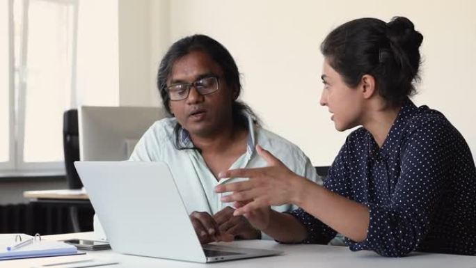 印度商人坐在办公桌前使用笔记本电脑讨论在线项目