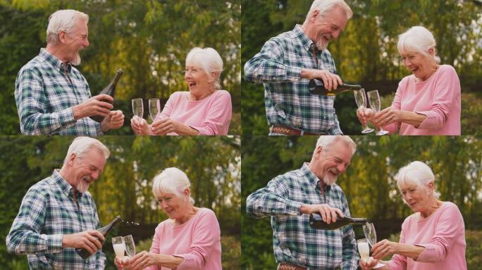 退休的高级夫妇庆祝好消息或赢得开幕式并在花园中倒香槟-慢动作拍摄