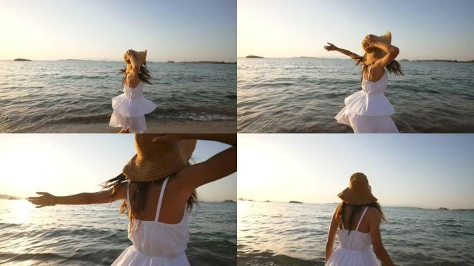 一个穿着白色夏装和草帽的年轻无忧无虑的女性游客的真实照片，在日落时的度假旅行中，她感觉很自由，在海景