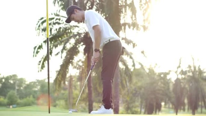 高尔夫球手以慢动作庆祝。职业亚洲男子高尔夫运动员在高尔夫比赛运动中将高尔夫球放入洞中后，为成功投篮感