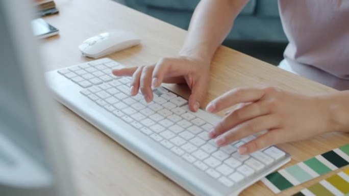 设计师在家工作时用键盘打字的女性手的特写