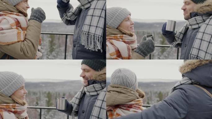 男人和女人徒步旅行者的倾斜在观景台上碰杯并欣赏冬季山脉的美景
