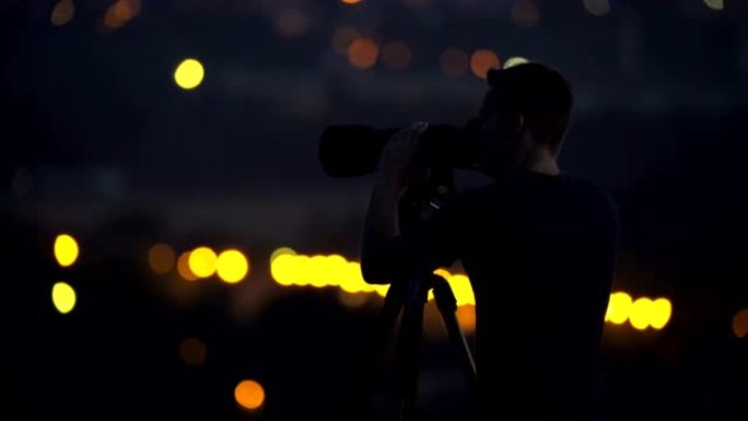 该名男子在夜市灯光的背景下使用相机工作。实时